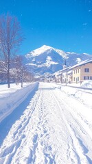 Fototapeta premium Snow-covered street with mountains in the background under a clear blue sky.