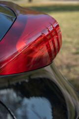 Fototapeta premium photo, close-up, car, taillight, glossy, red, automobile, detail, dark, signals, color, setting, outdoor, reflector, grass, light, hue, background, lamps, vehicle, exterior
