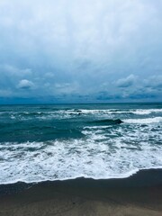 cloudy grey seascape, waved sea horizon, windy at the sea, empty beach