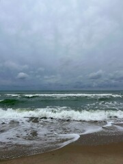 cloudy grey seascape, waved sea horizon, windy at the sea, empty beach