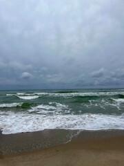 cloudy grey seascape, waved sea horizon, windy at the sea, empty beach