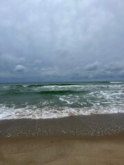 cloudy grey seascape, waved sea horizon, windy at the sea, empty beach