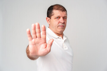 A middle-aged man wearing a white polo shirt holds up his hand