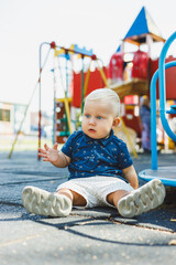 A little boy in a blue t-shirt and shorts is running on the playground. The child actively spends time playing and walking in the fresh air.