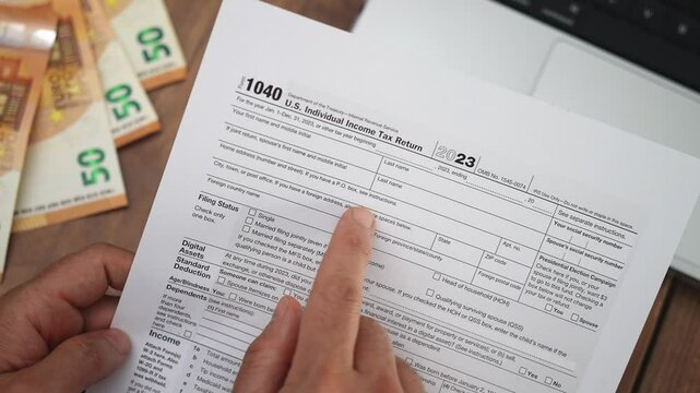 Entrepreneur reads Income Tax Return form at table contemplating reporting startup income and business expenses to determine eligible refund eligible for year in office