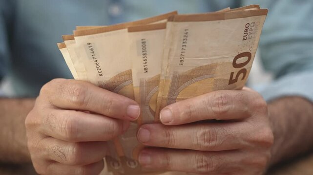 Mature businessman counts euro banknotes earned from successful international trade deal strategizing on reinvestment options to expand company global presence