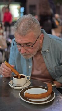 Elderly man with Parkinson's enjoying churros and chocolate, savoring a moment of indulgence