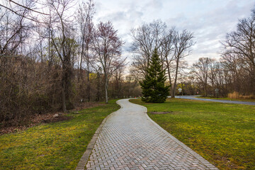Winding park pathway surrounded by trees and greenery on calm spring day in New Jersey.