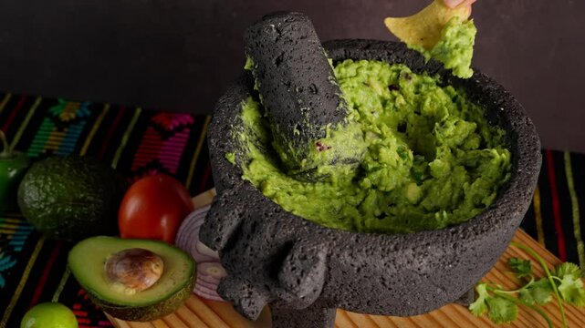 Mexican guacamole, a Mexican woman spreads guacamole on a tortilla chips, guacamole on a molcajete