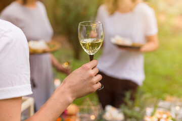 Female guests enjoying white wine tasting in a garden in summer