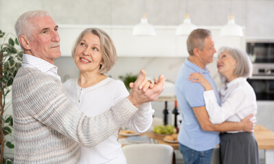 Couple dance at a house party in an apartment for elderly friends