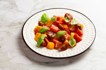 Salad with halves of red and yellow tomatoes cherry with basil