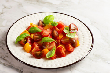 Salad with halves of red and yellow tomatoes cherry with basil