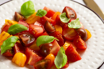 Salad with halves of red and yellow tomatoes cherry with basil