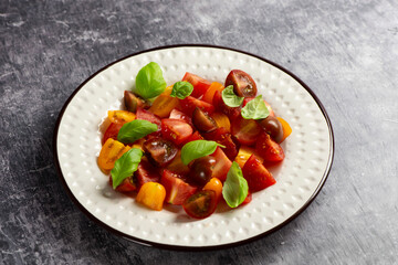 Salad with halves of red and yellow tomatoes cherry with basil