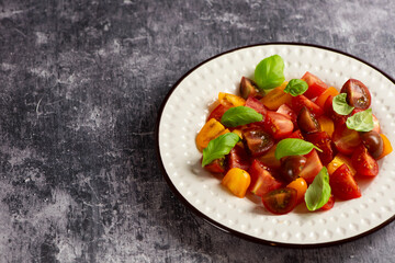 Salad with halves of red and yellow tomatoes cherry with basil