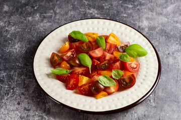 Salad with halves of red and yellow tomatoes cherry with basil