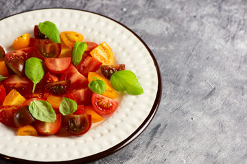 Salad with halves of red and yellow tomatoes cherry with basil