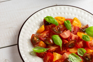Salad with halves of red and yellow tomatoes cherry with basil