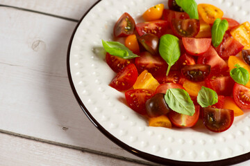 Salad with halves of red and yellow tomatoes cherry with basil