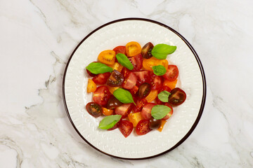 Salad with halves of red and yellow tomatoes cherry with basil