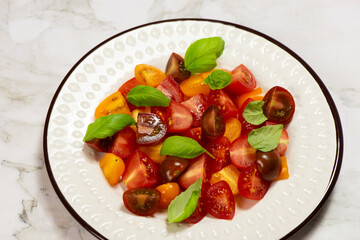 Salad with halves of red and yellow tomatoes cherry with basil