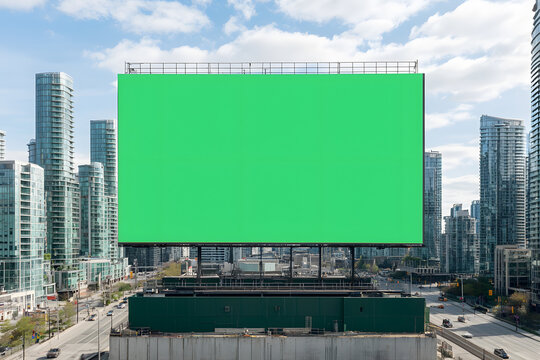 A large green screen billboard mounted on a building, ready for customisable digital content, standing out against the urban landscape.