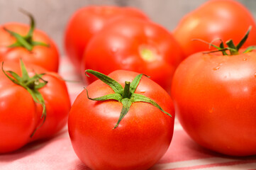 Freshly harvested tomatoes glistening under soft kitchen light on a striped cloth background