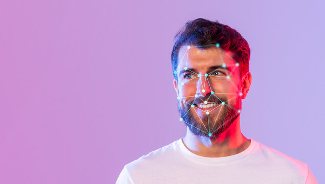 A young man with a beard smiles while facial recognition markers illuminate his face. The colorful background enhances the modern technology theme, creating a vibrant atmosphere. - Powered by Adobe