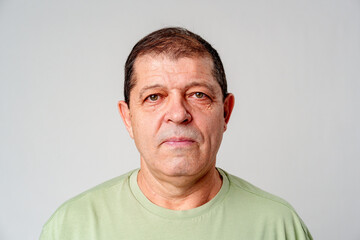 Obraz premium A mature man stands against a plain background, showcasing a calm expression