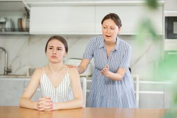 Mom calms down her adult daughter after a domestic quarrel in the kitchen