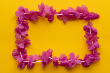 Vibrant pink flower lei on yellow background for tropical carnival celebration. 