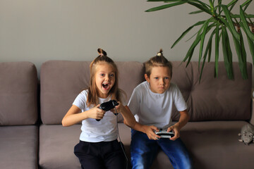 A lively scene of a boy and girl enthusiastically playing video games together at home. they...
