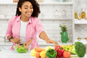 Casual black girl preparing healthy lunch for her family in modern kitchen, taking vegetables, copyspace