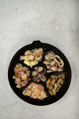 Finger food. Traditional seafood antipasti. Top view of a dish with different kinds of seafood preparations such as octopus, mussels with provencal, shrimps cocktail, pickles and kani kama salad	
