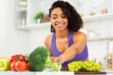 Lose Weight and Improve Health. Smiling black girl cooking at home in modern kitchen, copy space