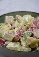 Seafood salad. Closeup view of a fresh salad with boiled sliced potatoes, chopped hard boiled egg, avocado, crab sticks and mayonnaise in a bowl on the white table