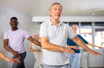 Dynamic mature attendees of dancing courses training Hip-hop dance poses in dancehall