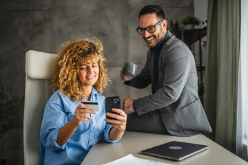 Adult man and woman colleagues buy online on mobile phone on break