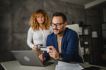 Adult man and woman colleagues buy online on laptop on break