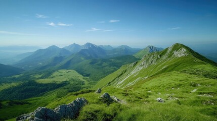 Obraz premium Rolling green hills and mountains stretch out as far as the eye can see on a bright, sunny day.