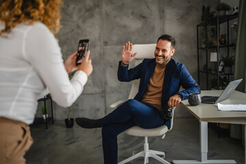 female colleague take a photo of her male colleague in the office