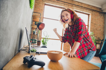 Excited woman celebrating gaming victory at home office desk
