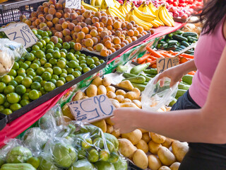 woman buying potatoes and vegetables at the market, concept buying vegetables