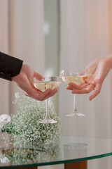 two people holding champagne glasses with one being held up to the other with a flower in the background.