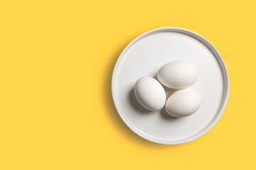 egg in a white plate on yellow background. Top view