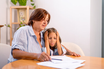 Obraz premium Depressed granddaughter and concerned grandmother review financial bills together, sharing tense and emotional moment as they face financial challenges at home 