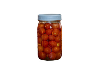 Mason jars filled with fermenting cherry tomatoes and cabbage on a kitchen counter top surrounded by dried corn and sugar pumpkins