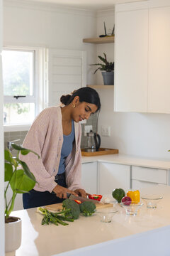 Asian woman chopping vegetables in modern kitchen, preparing healthy meal, at home