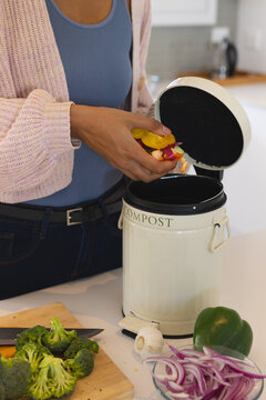 Composting vegetable scraps in kitchen, woman promoting eco-friendly lifestyle, at home